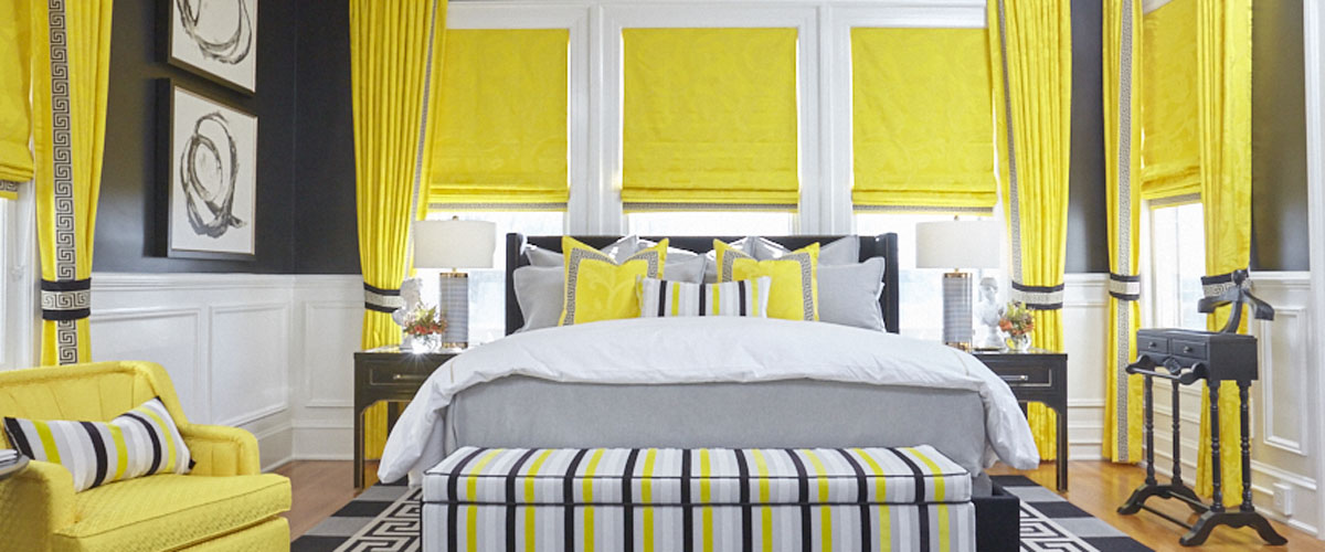 Fabric Roman shades paired with draperies in a bedroom